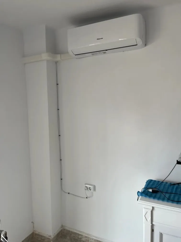 Aire acondicionado split instalado en la pared de un dormitorio, con la canaleta del cable