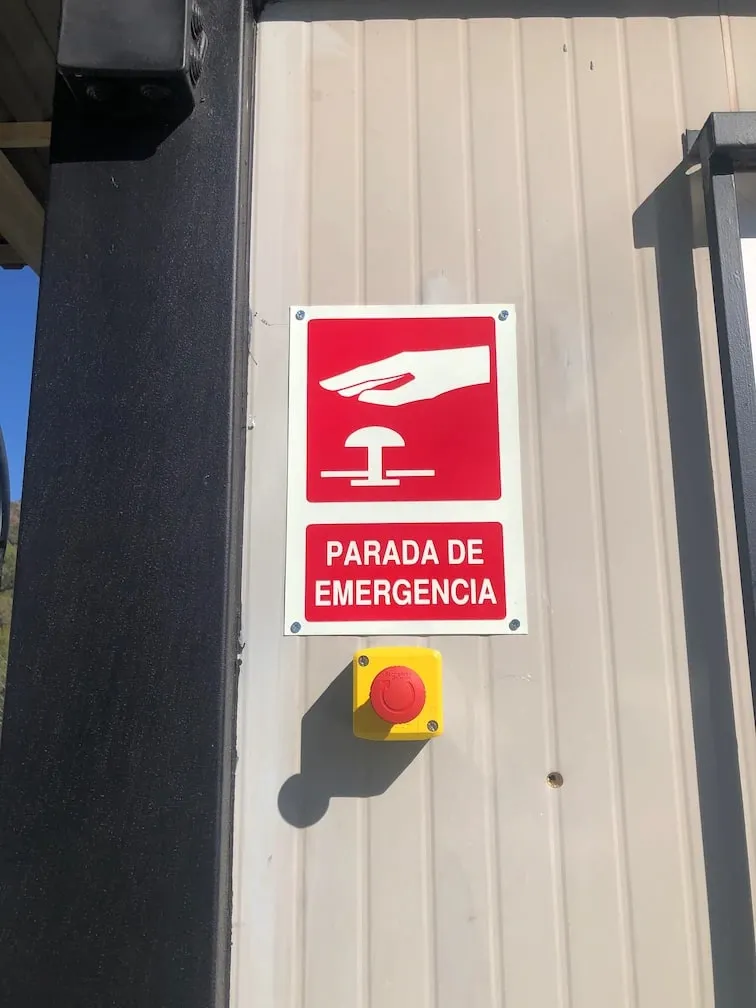 Pulsador de parada de emergencia con su señal, instalado en la pared de una nave