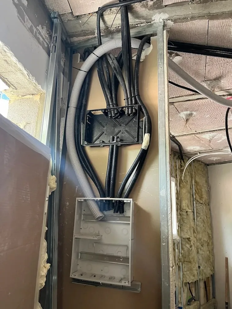 Caja del cuadro empotrada en una pared en obra, con los tubos de los circuitos llegando desde el techo