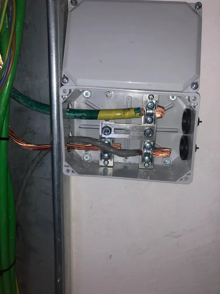 Caja de conexión de la toma de tierra con la pletina de cobre y los cables de protección